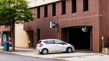 A white car parked in front of a building with a parking sign.