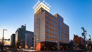 A multi-story hotel with a prominent sign at the top, multiple windows, and a modern architectural design. - Obihiro Tennen Onsen Fukui Hotel (Obihiro)