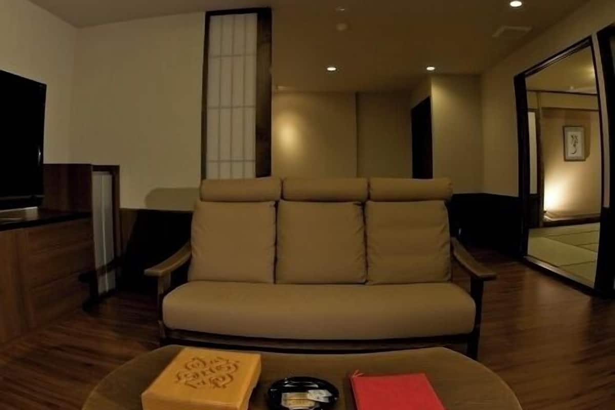 Una sala de estar moderna con un sofá, una mesa de centro con libros y un control remoto, y un espejo grande.