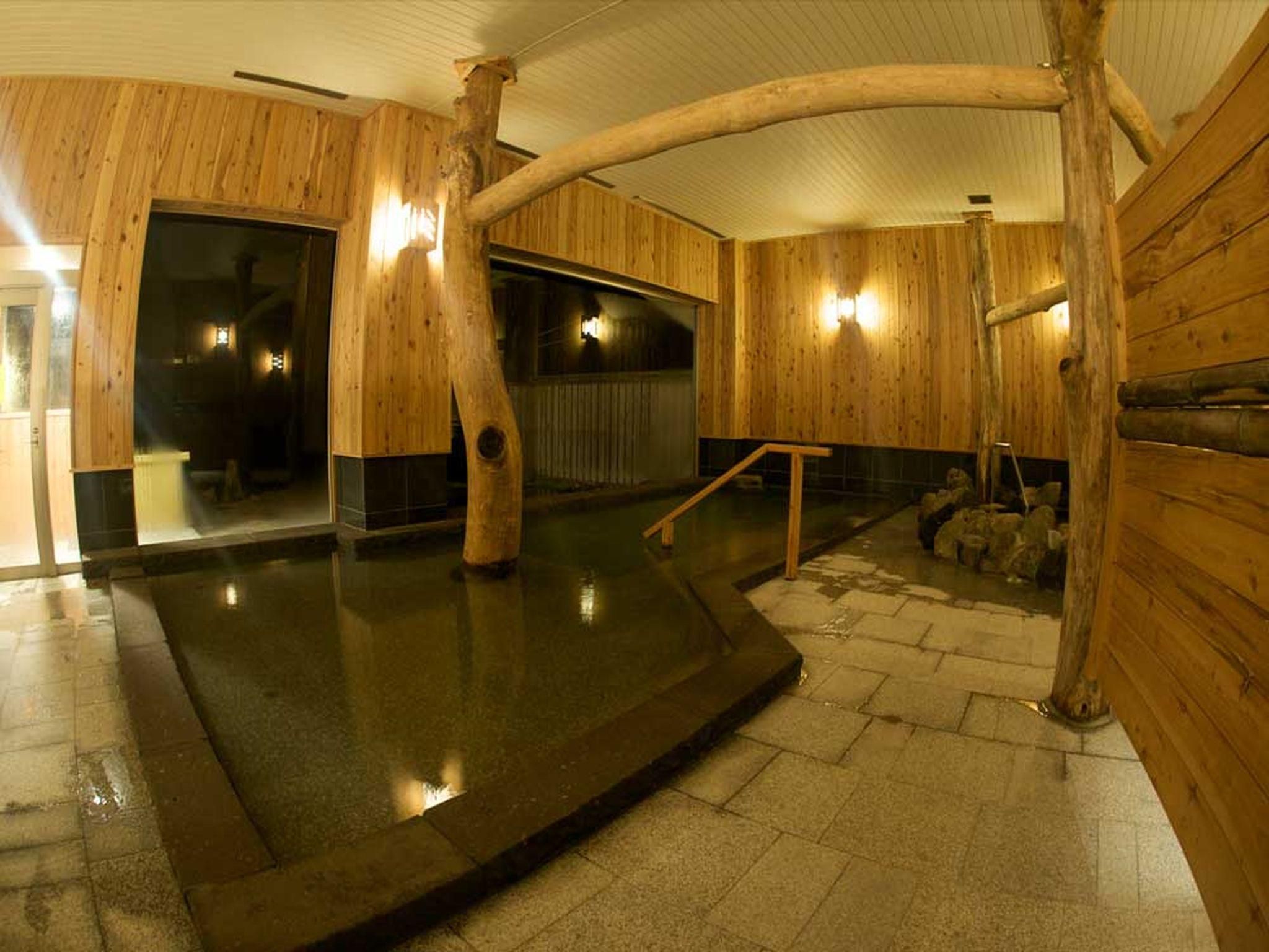 Un interior de madera con un jacuzzi, suelo de piedra y paredes de madera.
