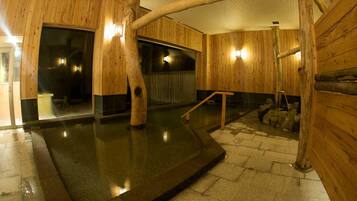 Un interior de madera con un jacuzzi, suelo de piedra y paredes de madera.