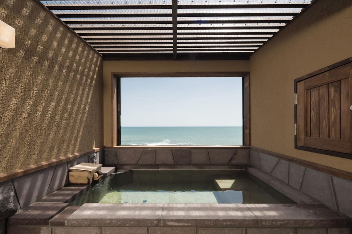 Un jacuzzi con vista al océano, una puerta de madera y una pared con textura.