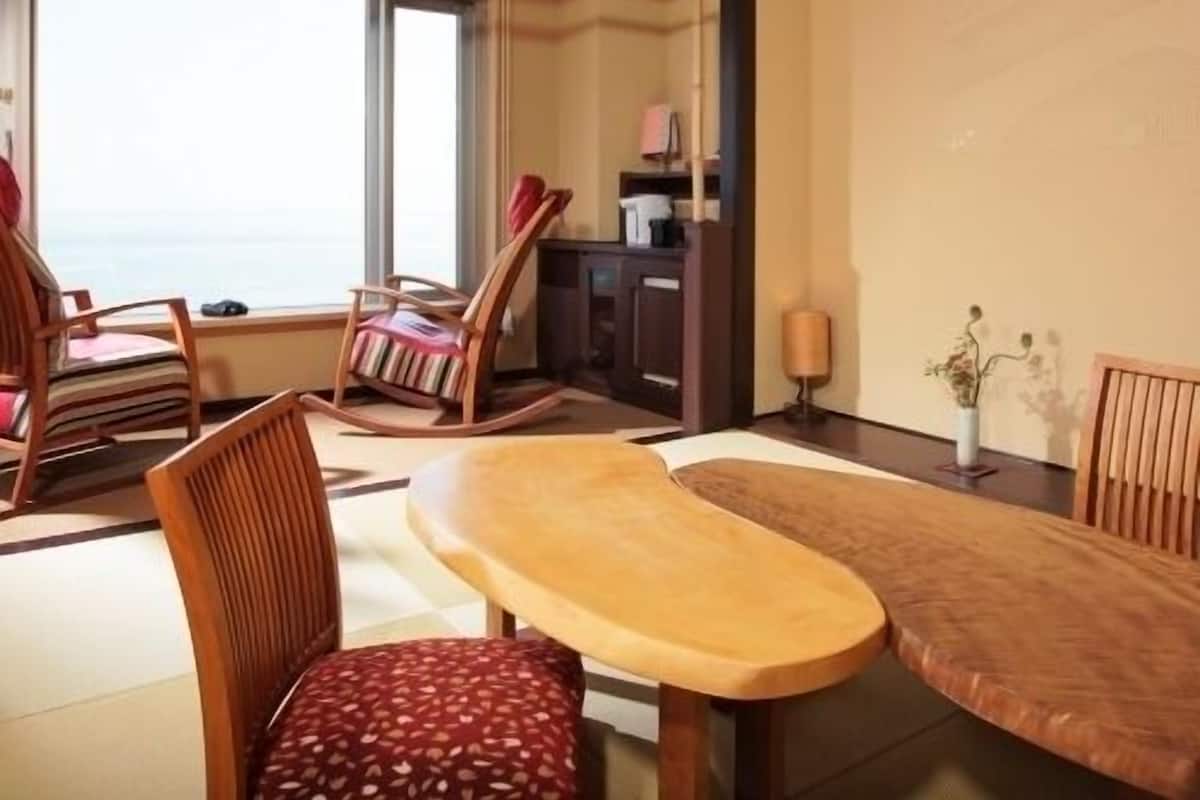 Una habitación con techo de madera, un ventanal grande, una mesa de comedor y dos mecedoras.