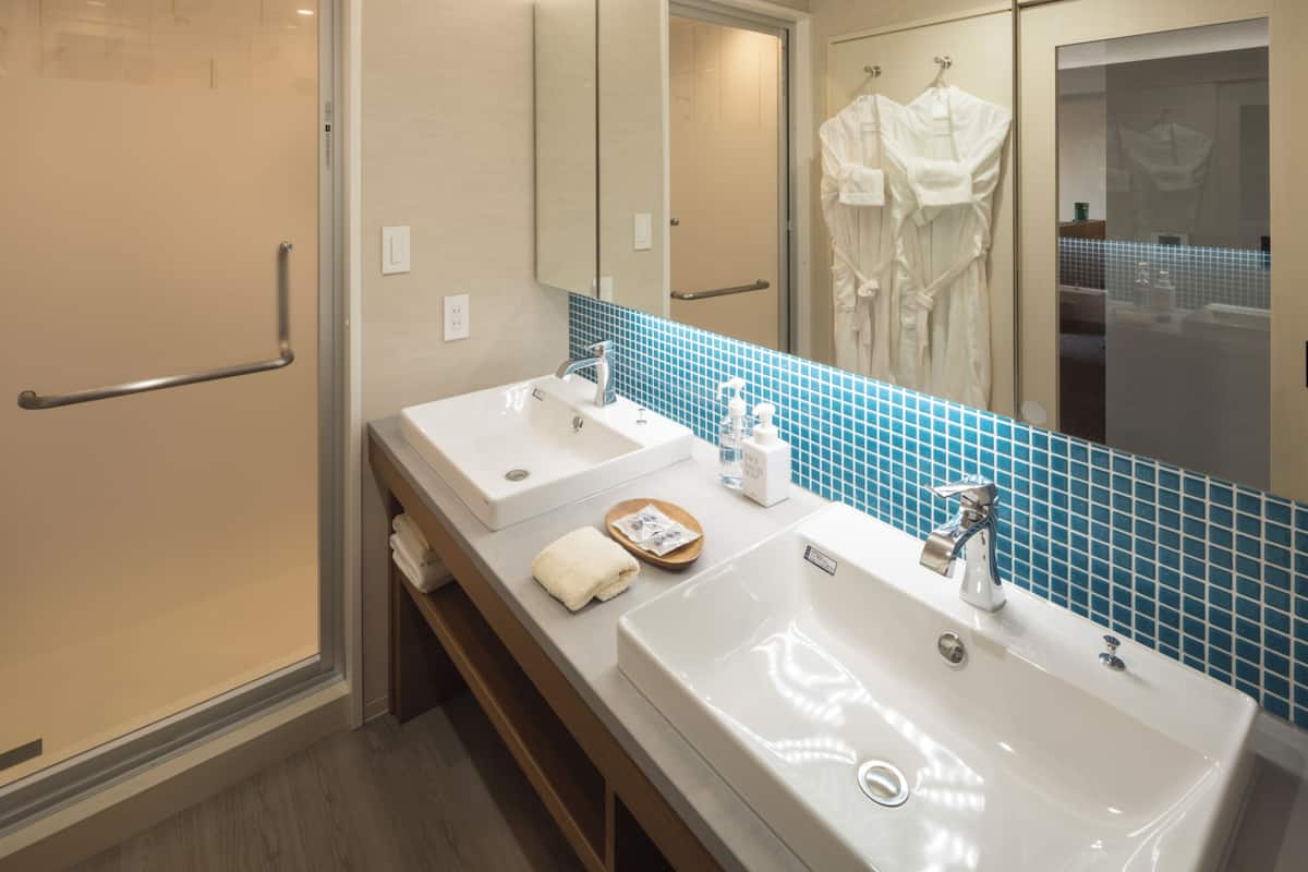 Un baño con dos lavamanos, un espejo y una zona de ducha.