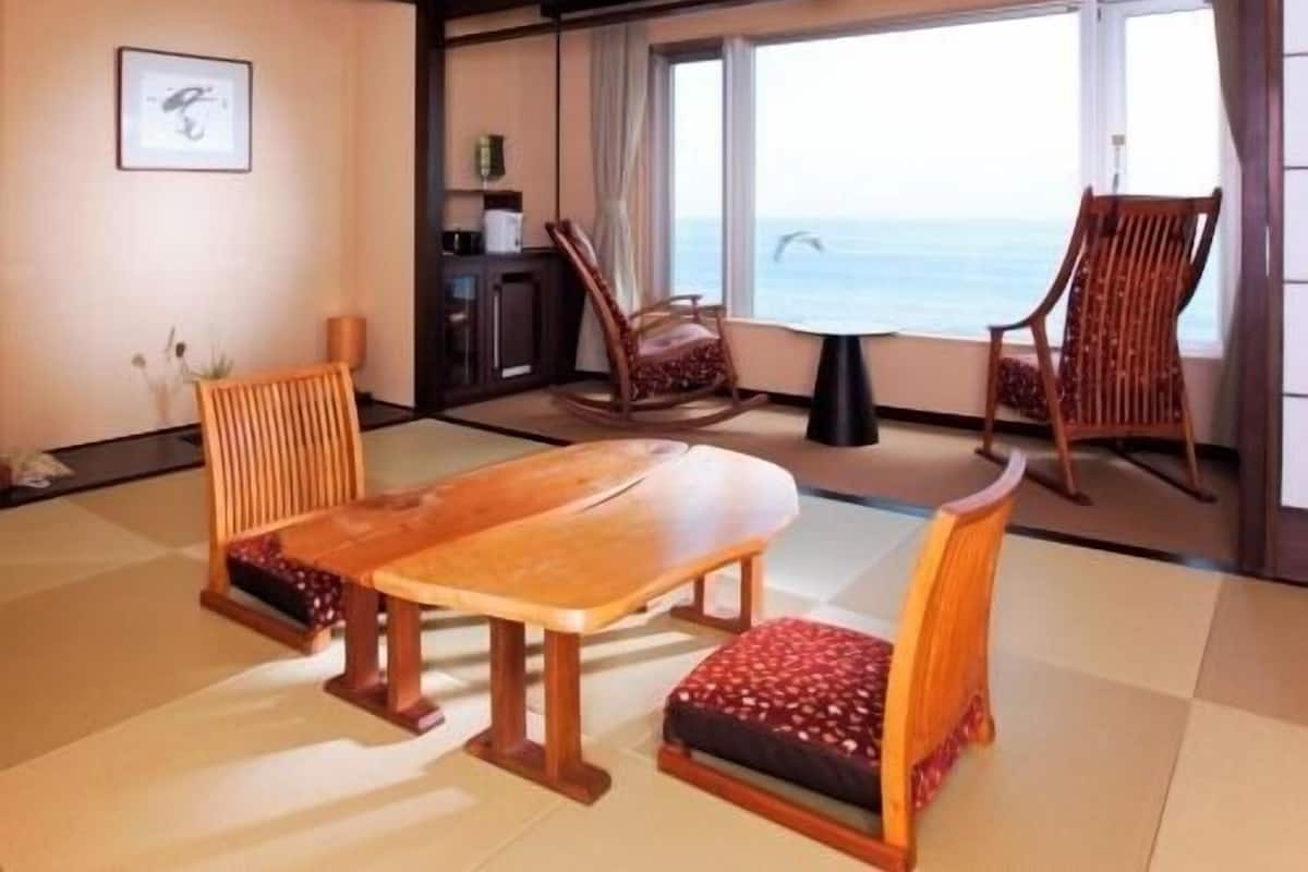 Una habitación con una mesa y sillas de madera, vista al mar y un ventanal grande.
