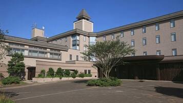 A multi-story building with a central courtyard, a covered parking area, and a small tower-like structure on the roof.