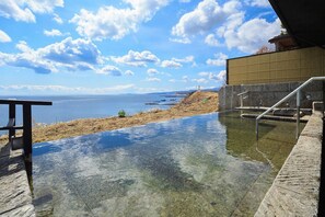 Una piscina infinita con vistas despejadas al mar y un faro distante.