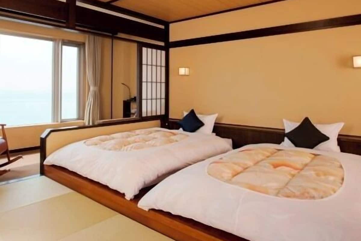 Una habitación de hotel con dos camas, un ventanal amplio y techo de madera.