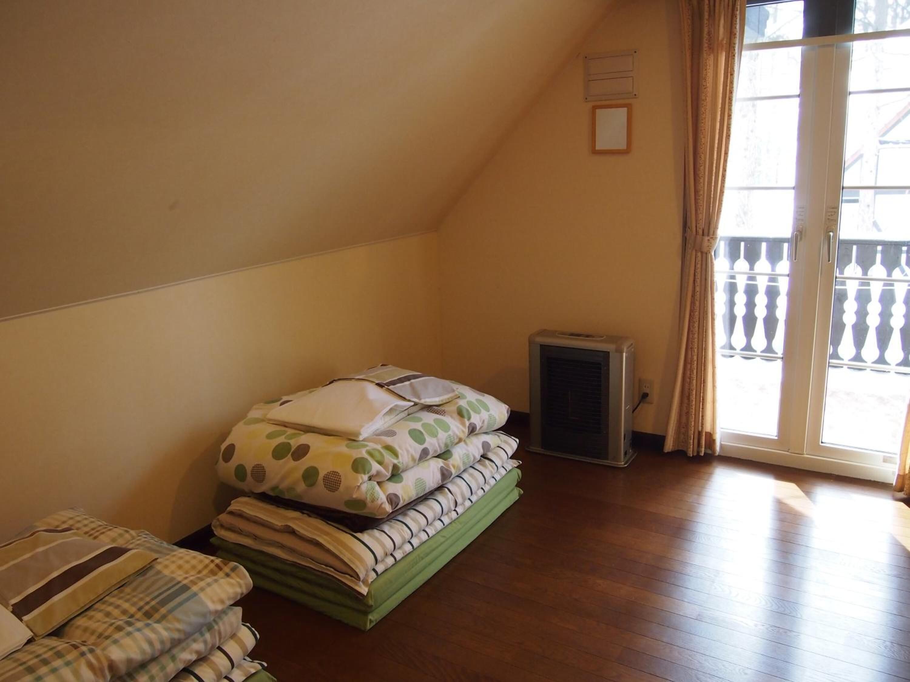 Un dormitorio con cama, calefactor y ventana con vista a un balcón.