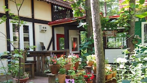 A rustic outdoor seating area with wooden benches and a variety of potted plants.