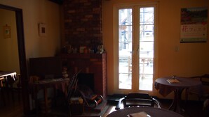 A cozy room with a brick fireplace, a dining table, and a large window with a view of the outside.
