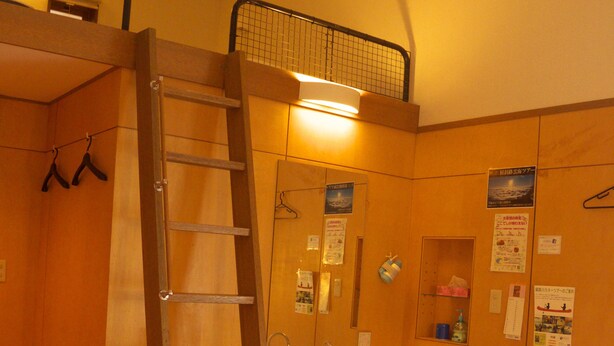 Un dormitorio con una cama nido, una escalera de madera, un lavamanos y un espejo.