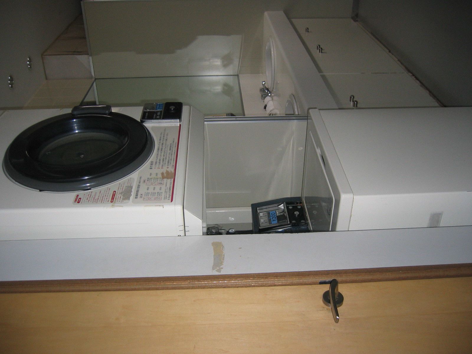 A laundry room with stacked washing machines and dryers, a metal basin, and a wooden counter.
