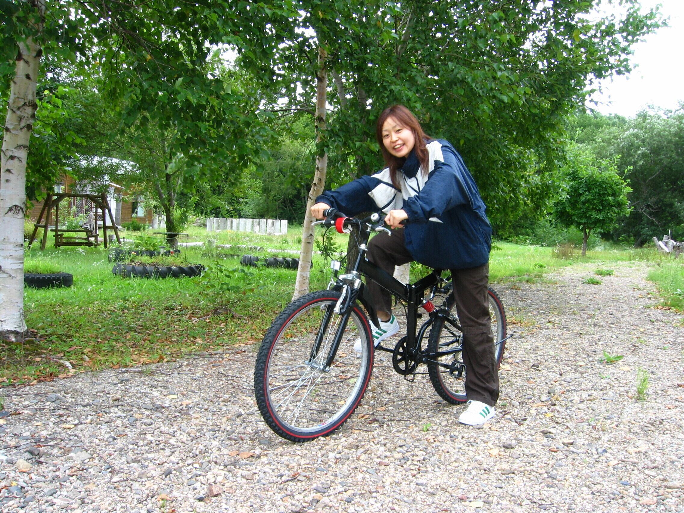 Una persona en bicicleta en un parque con árboles y un camino de grava.
