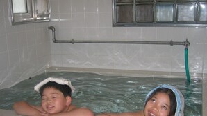 A bathtub with tiled walls and a metal faucet. - Kussharo Genya Youth Guesthouse – Hostel (Teshikaga)