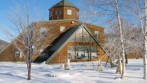 Una cabaña de madera con techo inclinado y una pequeña estructura en forma de torre.