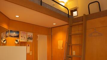 Een kamer met een stapelbed, een trapje, een radiator en een lamp.