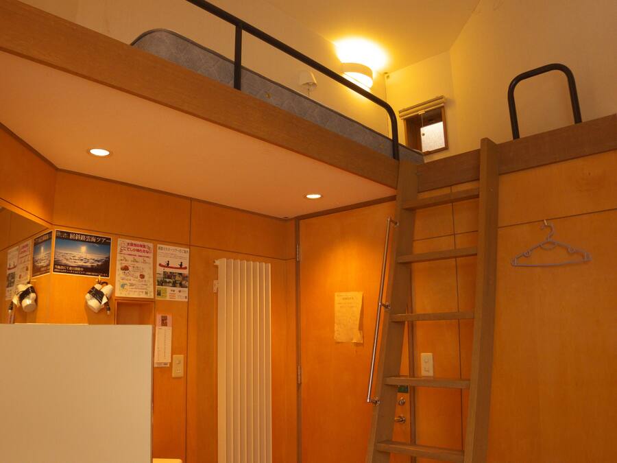 Een kamer met een stapelbed, een trapje, een radiator en een lamp.