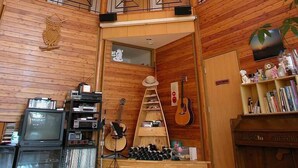 A spacious, multi-level interior with wooden paneling, a piano, and various musical instruments. - Kussharo Genya Youth Guesthouse – Hostel (Teshikaga)