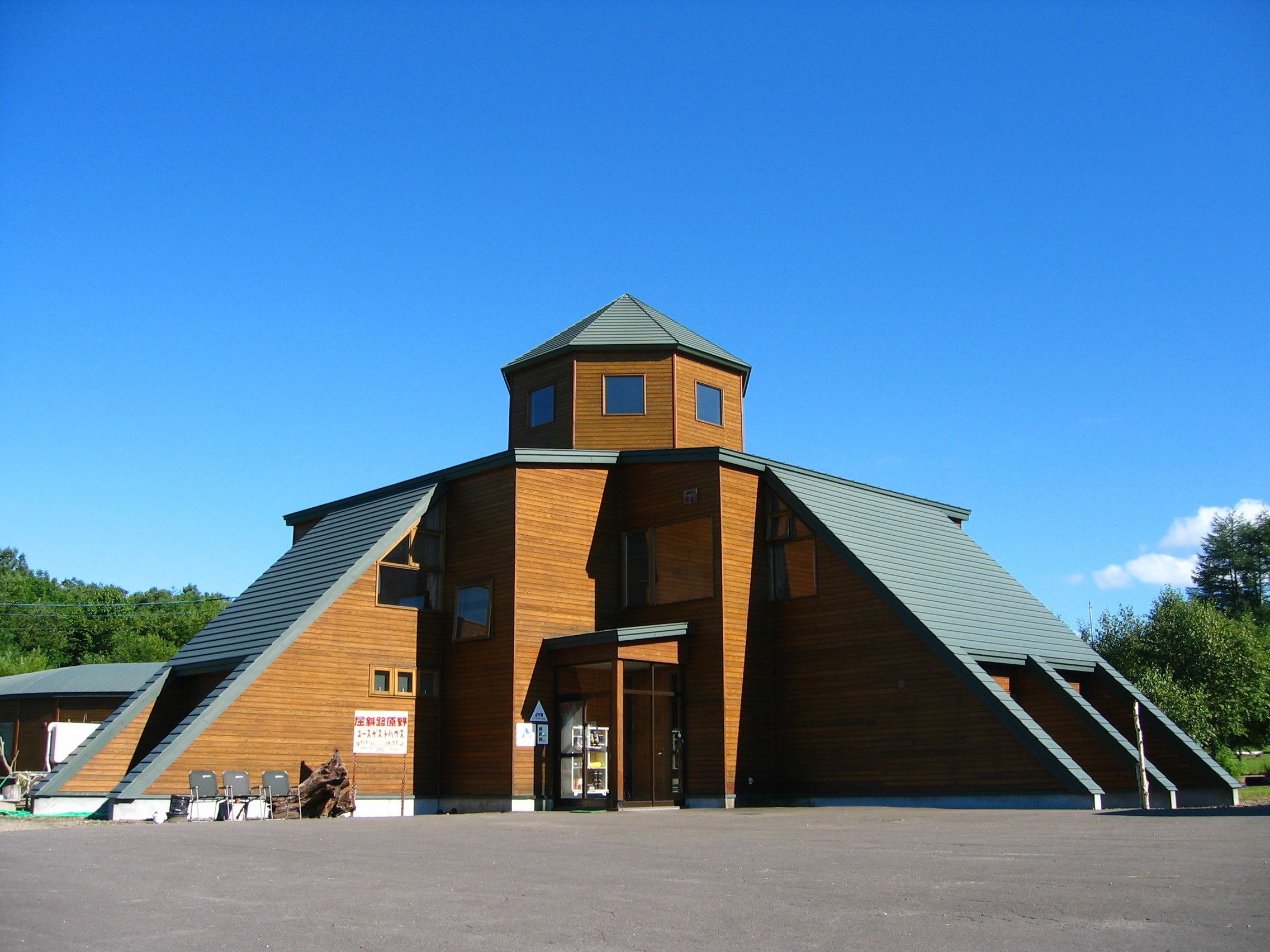 A large wooden building with a steeply pitched roof and a small tower on top.