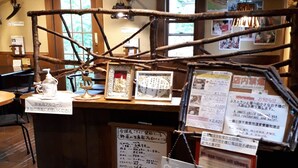A rustic interior with a wooden counter displaying various items and signs, a traditional woven rug, and a wooden stool with a person standing on it. - Pension & Restaurant Bistare Kana (Niseko)