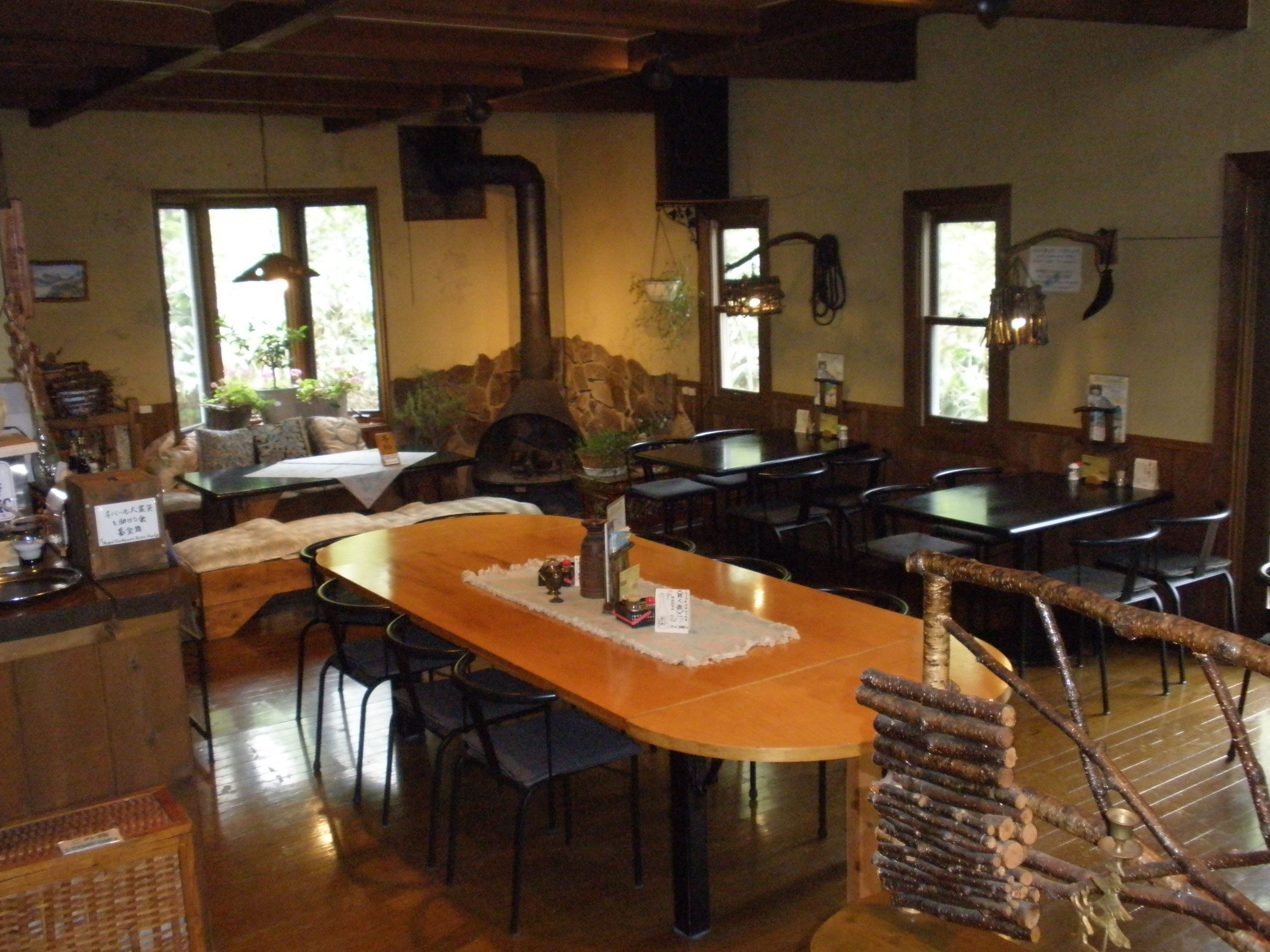 A restaurant with a rustic interior, featuring a stone fireplace, wooden tables, and chairs.