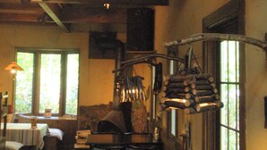 A rustic interior with a wooden ceiling, a fireplace, and a dining area with chairs and tables. - Pension & Restaurant Bistare Kana (Niseko)
