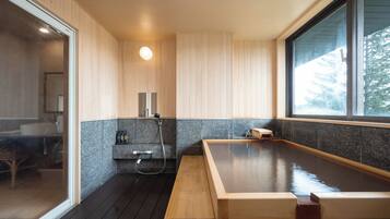 A modern bathroom with a wooden bench, a built-in sink, and a large window.