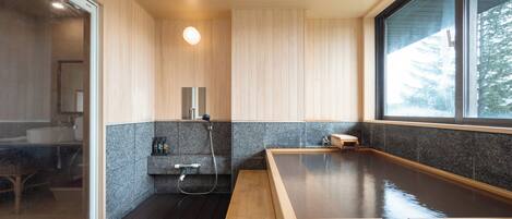 Een moderne badkamer met een houten bankje, een inbouwspoelbak en een groot raam.