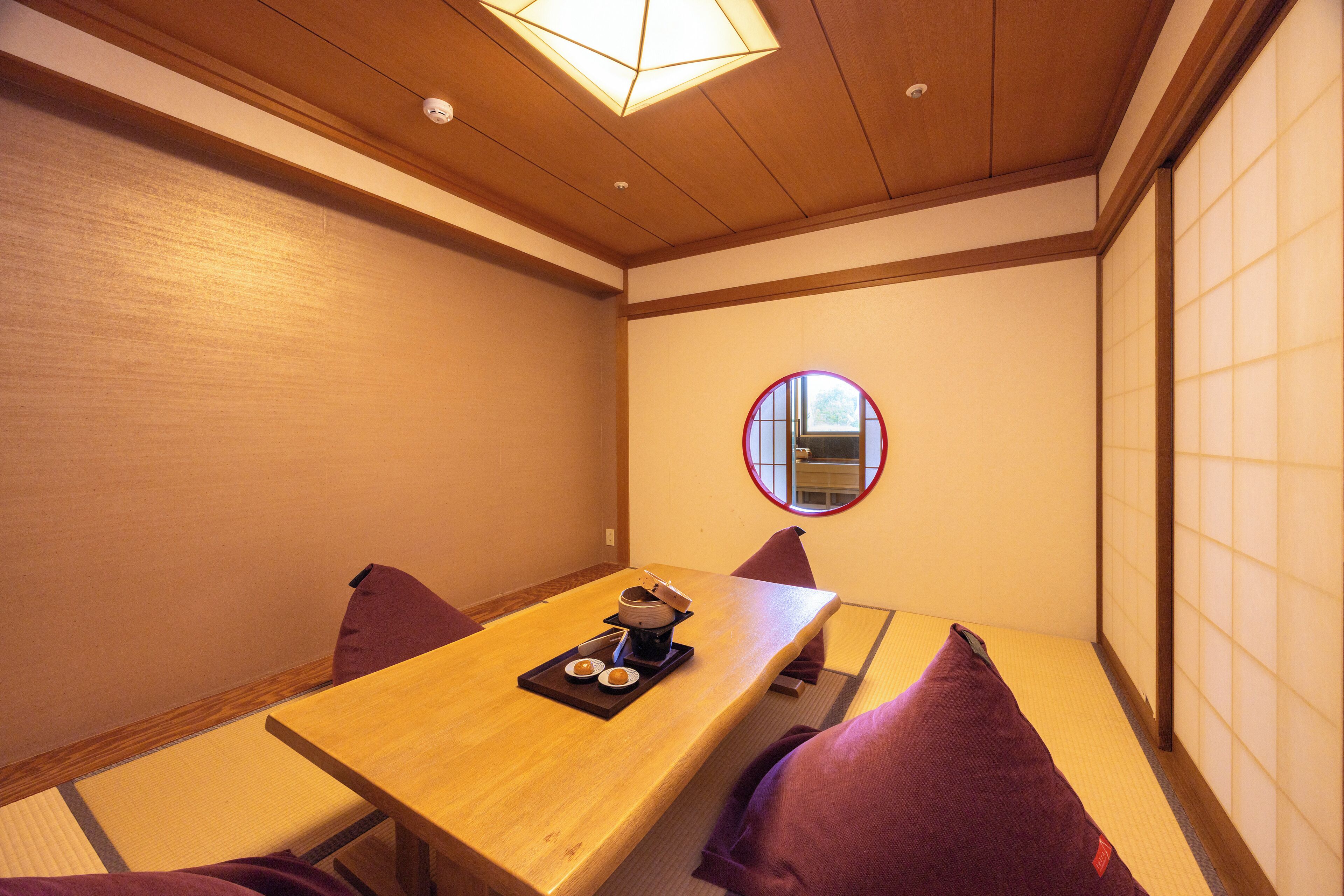 A traditional Japanese room with tatami flooring, a wooden table with a tea set, and shoji screens.