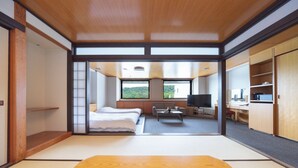 A modern interior with a bed, sofa, TV, and kitchenette.