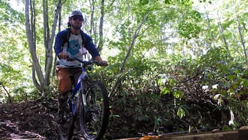 Una persona montando una bicicleta de montaña sobre un puente de madera en un bosque.