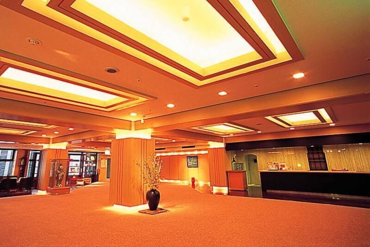 A spacious lobby with a central column, recessed lighting, and a reception desk.