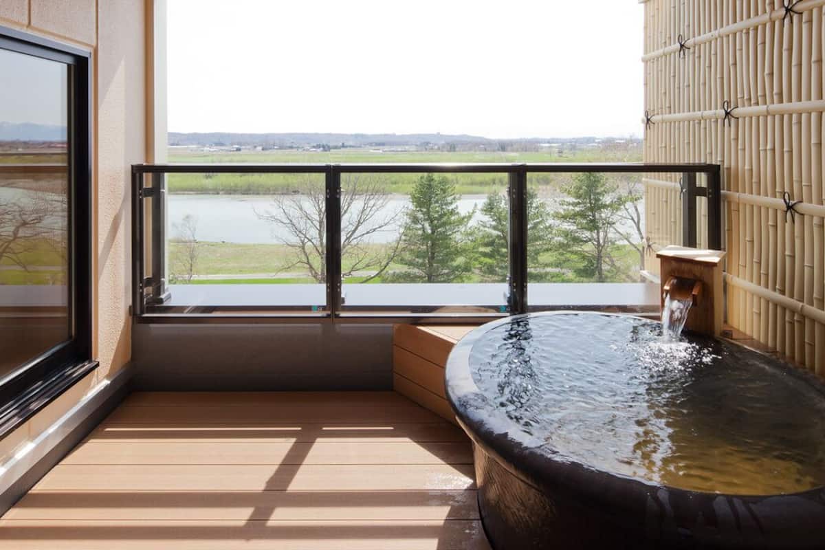 Un jacuzzi en un balcón con vistas a un lago y árboles.