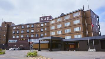 A multi-story hotel with a brown facade, multiple windows, and a covered entrance.