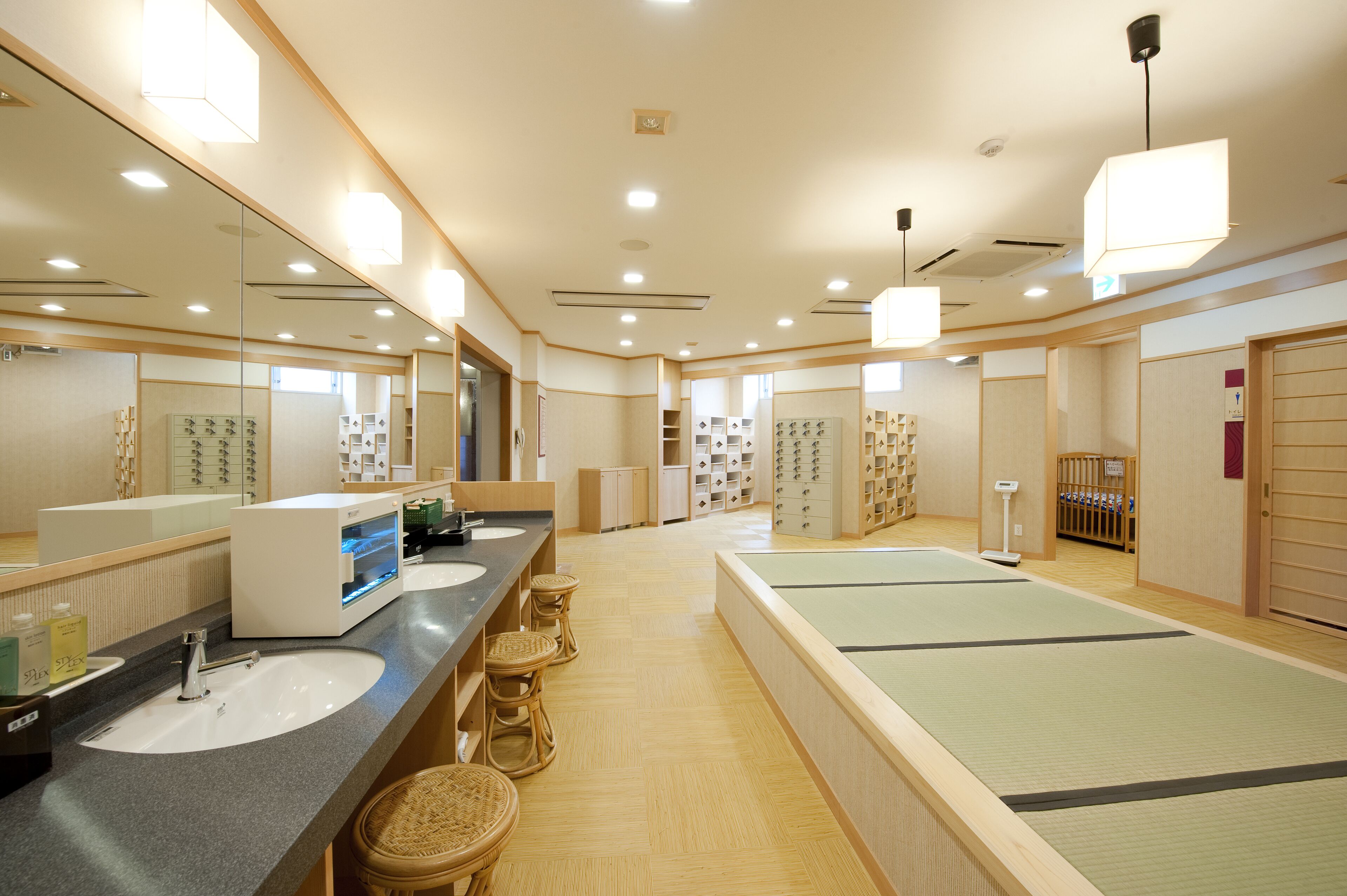 Ein Hotelbad mit mehreren Waschbecken, Spiegeln und einer Zone mit Tatami-Matten.
