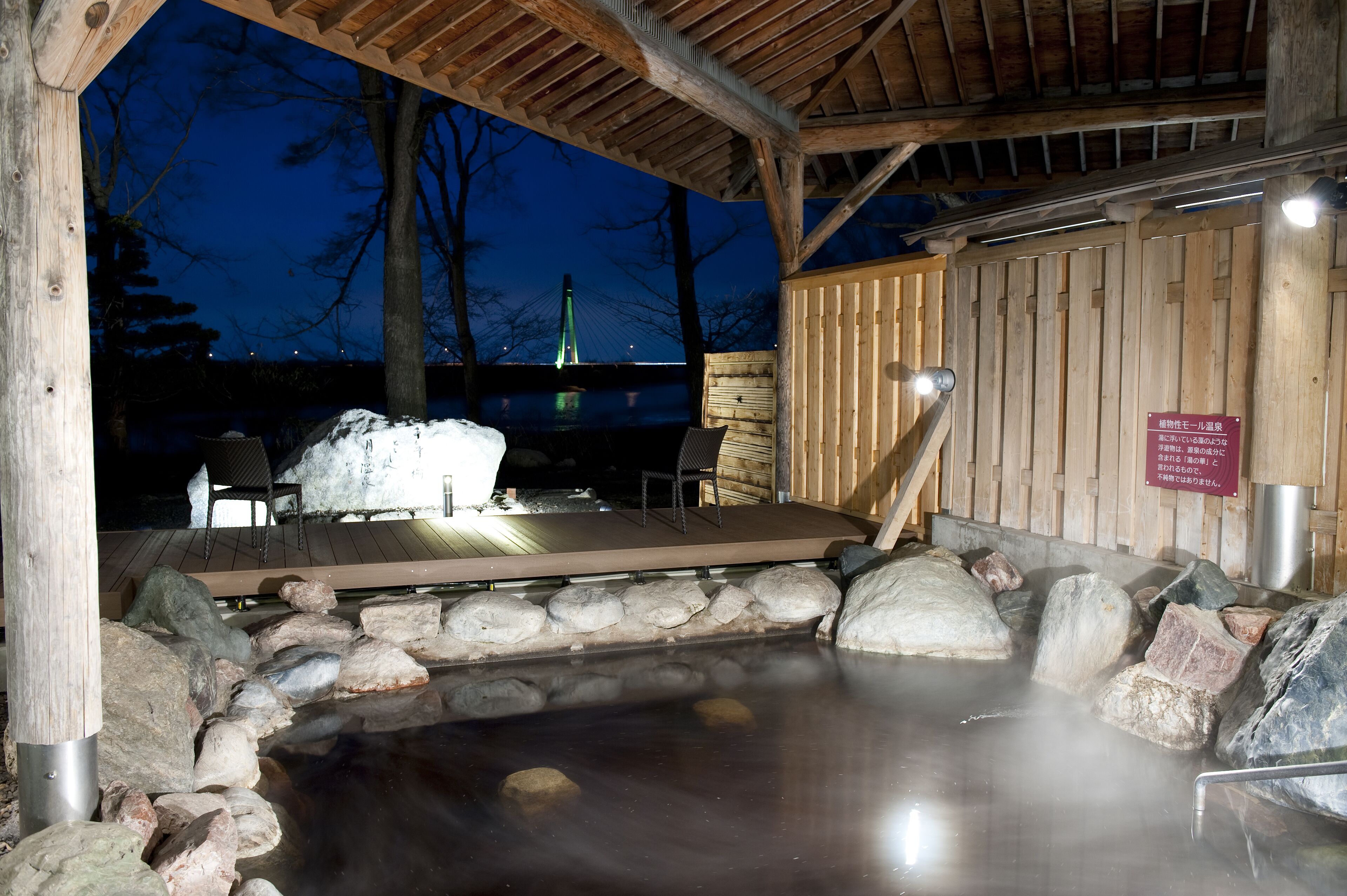 A hot spring area with wooden benches and a stone wall.