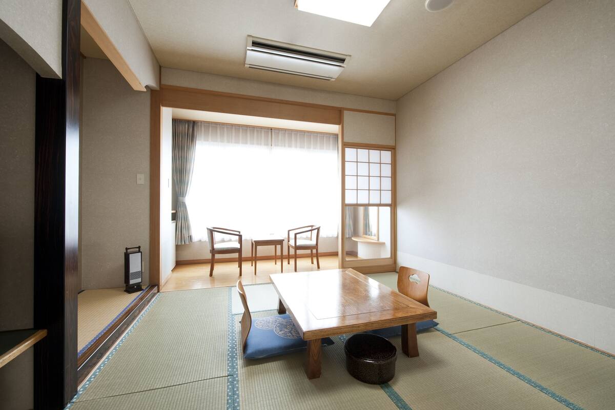 A traditional Japanese room with tatami flooring, a low table, and four chairs.