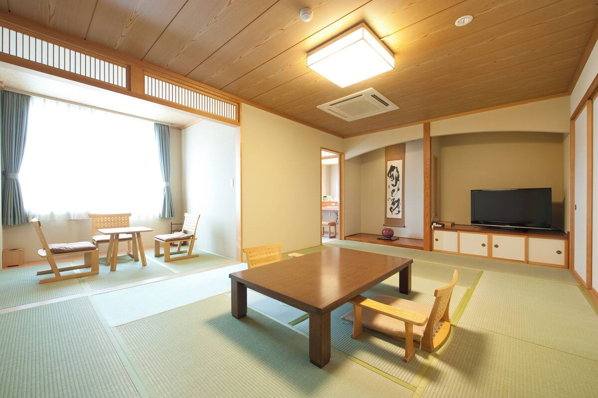 A traditional Japanese-style living room with tatami flooring, a low wooden table, and a television.