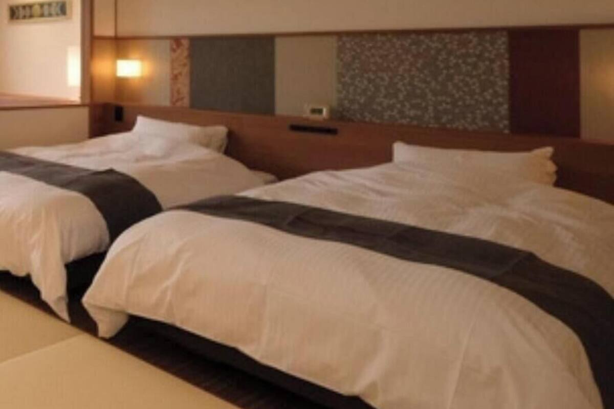 A hotel room with two beds, a headboard with a mirror, and a wall-mounted light.