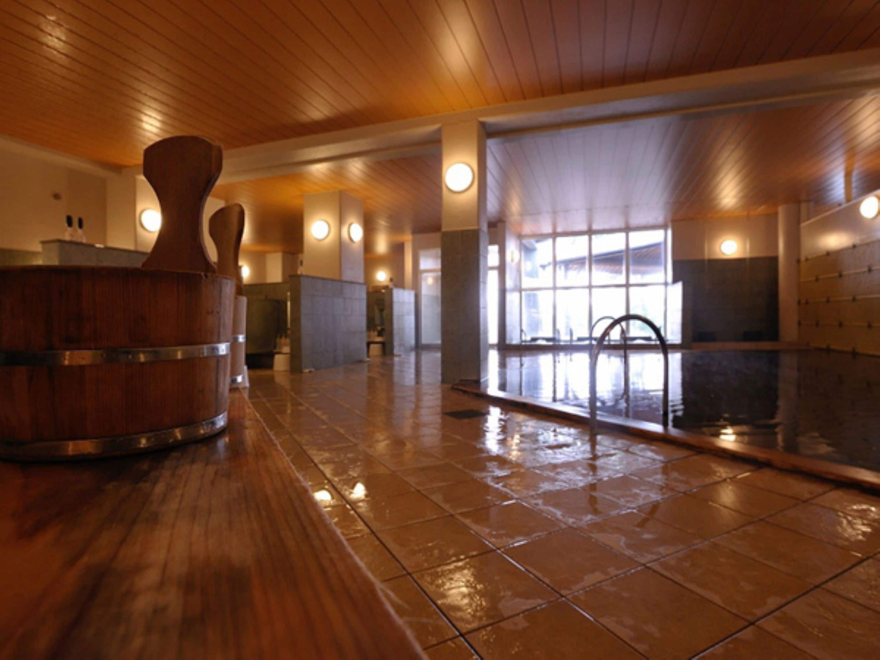 A spacious indoor swimming pool with wooden flooring and a large window providing natural light.