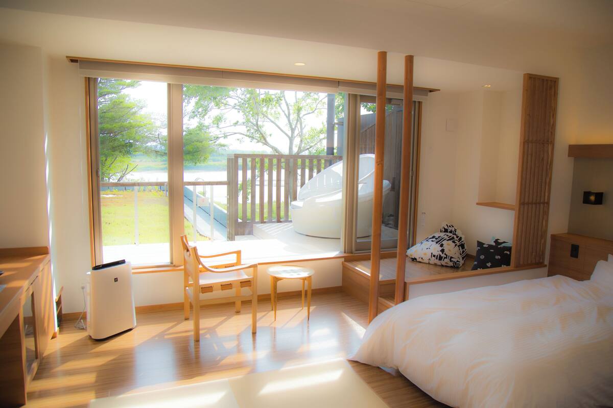 A modern bedroom with a large window, a bed, a desk, and a chair.