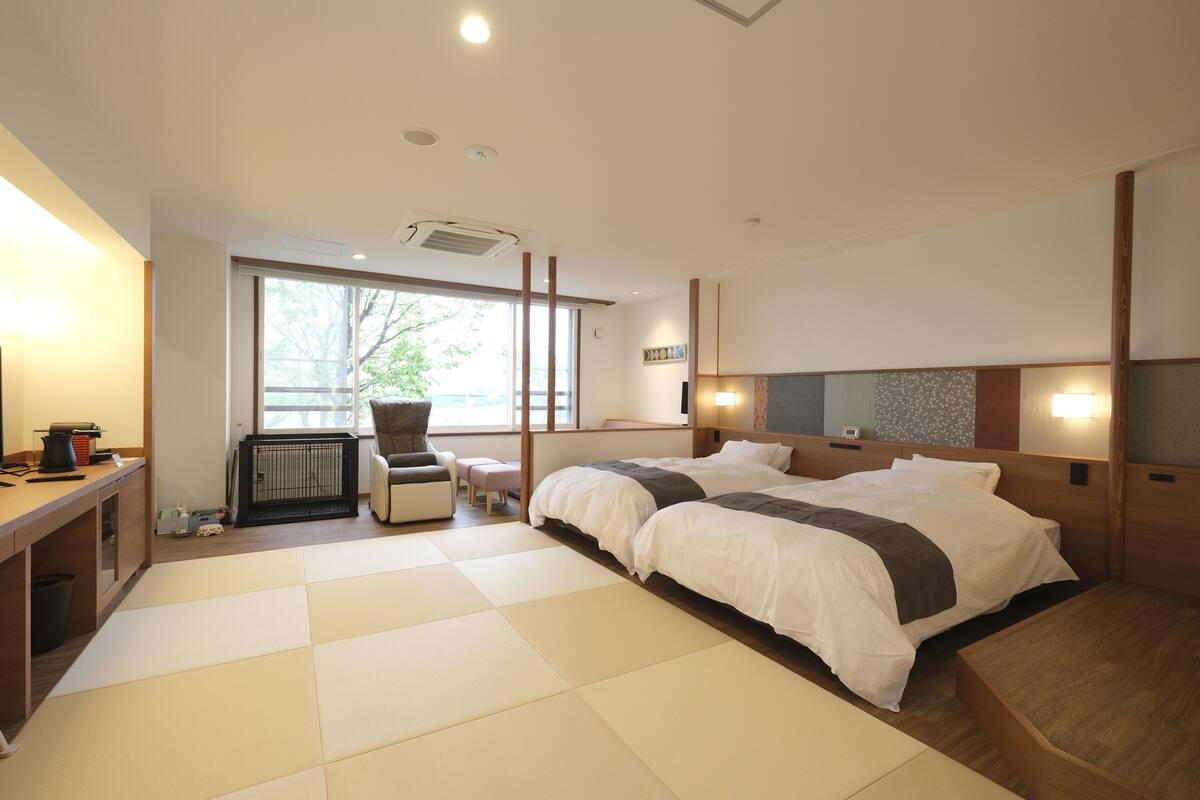 A hotel room with a large bed, a desk, a chair, and a small table.