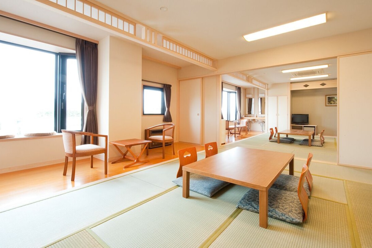 A traditional Japanese room with tatami flooring, a low table, chairs, and sliding doors.
