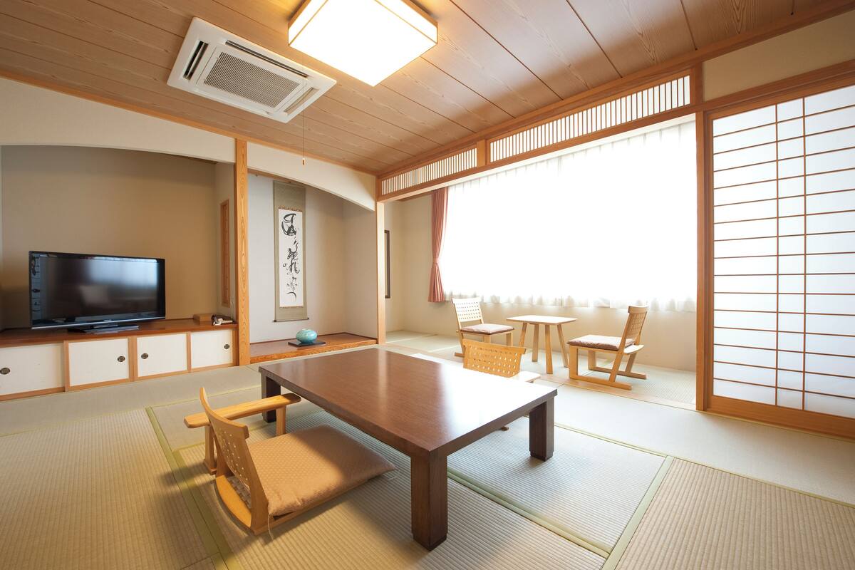 A traditional Japanese room with tatami flooring, a low table, and a television.