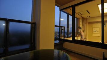 Una habitación con ventanas amplias, vista a un puente y una persona con un vestido estampado.