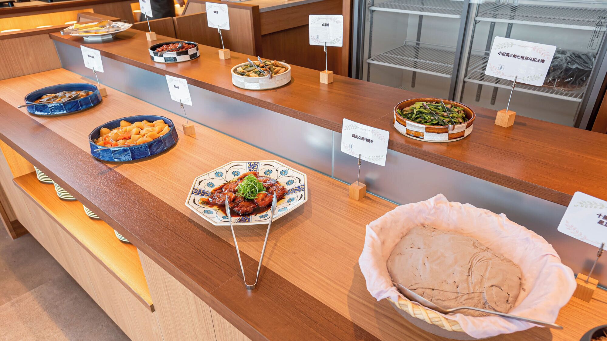 Een buffet met diverse gerechten gepresenteerd in kommen en schalen, elk met een bordje.