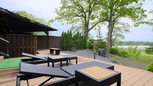 A deck with outdoor furniture, a wooden structure, and a view of the landscape. - Kangetsuen (Otofuke)