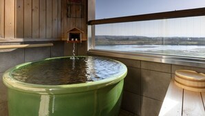 A large green water feature in a room with a wooden bench and a window overlooking a landscape. - Kangetsuen (Otofuke)