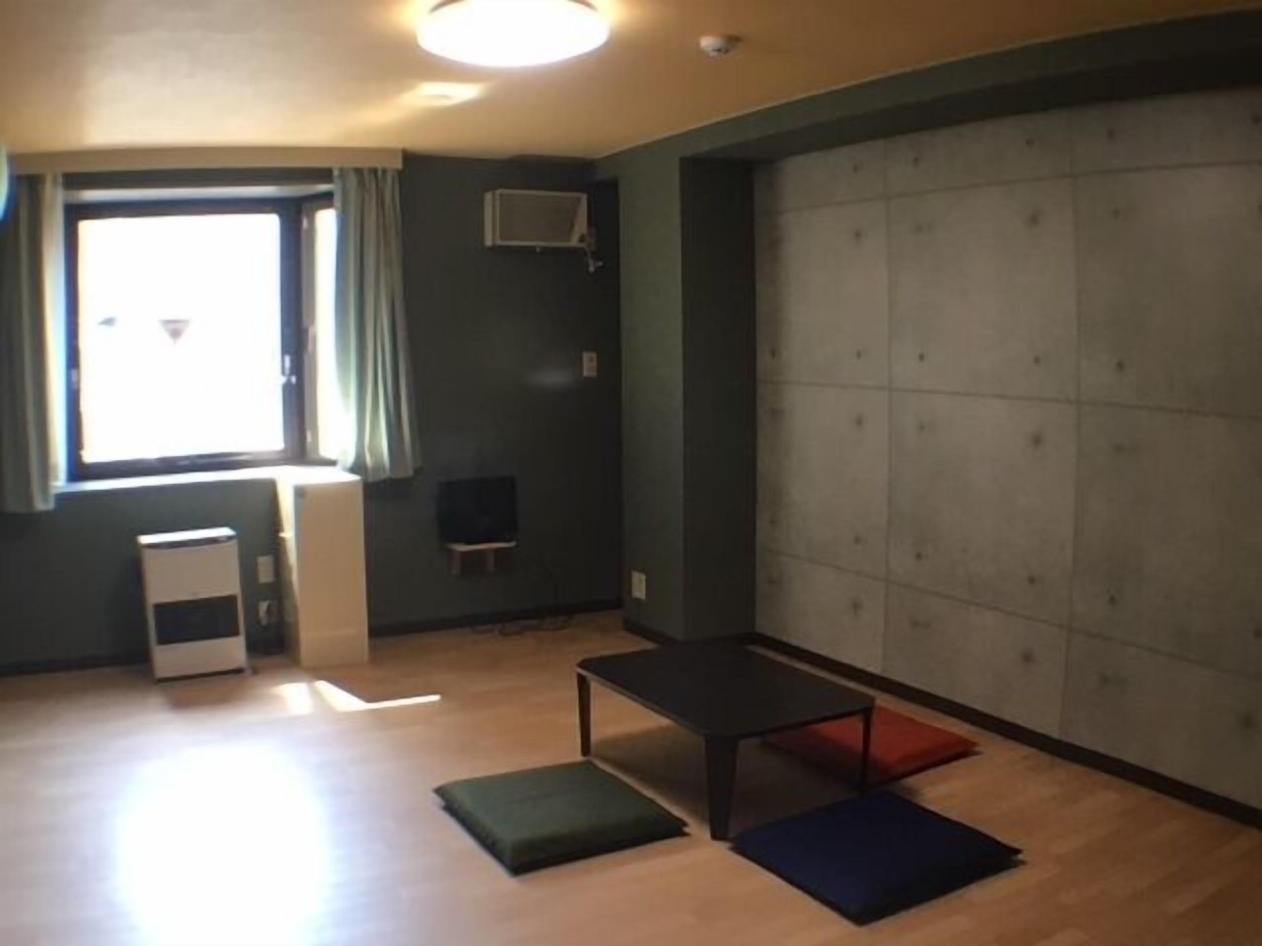 A room with a large window, a small table, a bench, and a padded seating area.